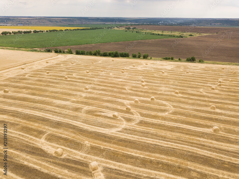 Naklejka premium aerial top view to harvested field with straw bales in summer
