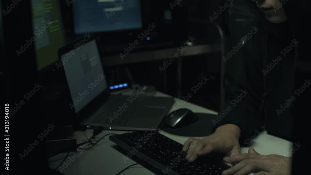 Hacker connecting with his computers in a dark basement Hacker connecting with his computers in a dark basement