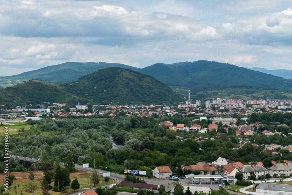 green city, houses with red roofs on a mountain plain under a cloudy cloudy sky green city, houses with red roofs on a mountain plain under a cloudy cloudy sky