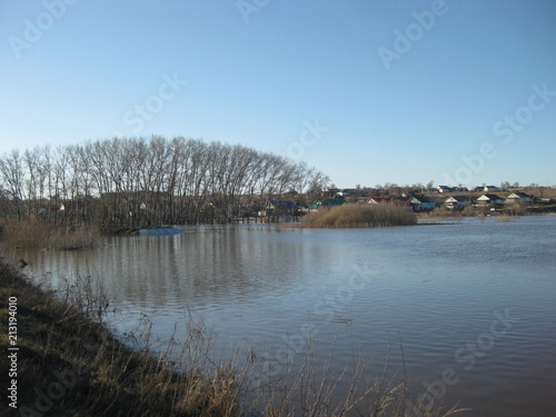 Spring snowmelt, which led to the flood of the river in Central Russia. In the foreground, blue water is a river that has come out of the banks. Water spilled across the plain, flooding roads and tree