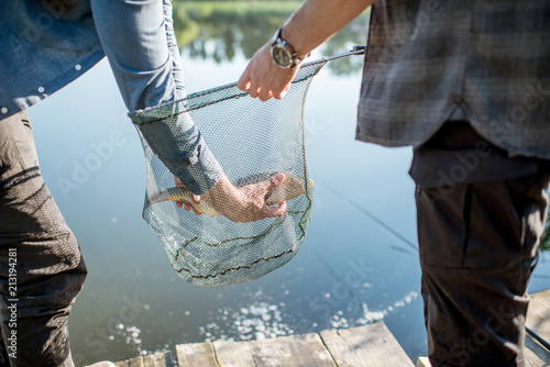 Canvas Print Fisherman getting caught fish from the fishing net near the lake in the morning