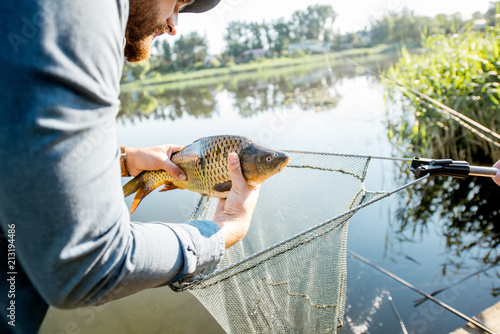 Canvas Print Fisherman getting caught fish from the fishing net near the lake in the morning