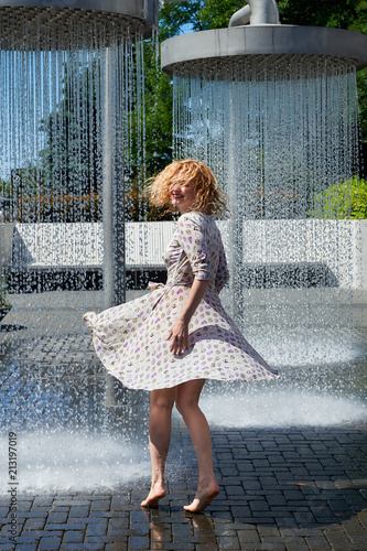 Young woman wearing a multicolored dress in a water bath.