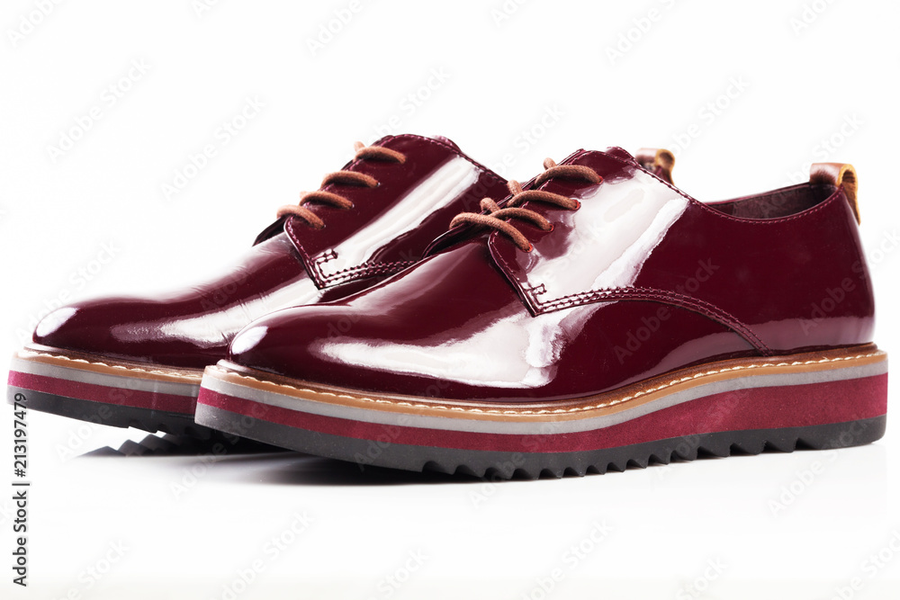 Deep red shiny pair of shoes on a white background. Deep red shiny pair of shoes on a white background.