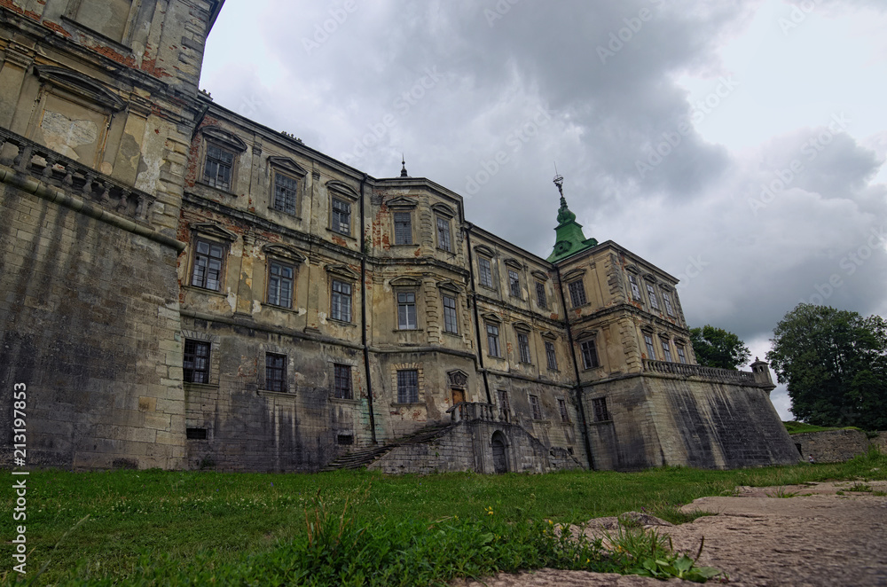 Medieval Pidhirtsi Castle at cloudy summer day, several minutes before rain. Village Pidhirtsi, Lviv region, Ukraine. Selective focus with wide angle lens