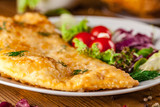 Uzbek eastern Tatar cuisine, cheburek with meat and suluguni cheese in a white plate with vegetables and greens on a wooden table.