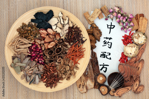 Chinese acupuncture needles with traditional herbs used in herbal medicine with calligraphy script on bamboo background. Translation reads as chinese alternative medicine. Top view. photo