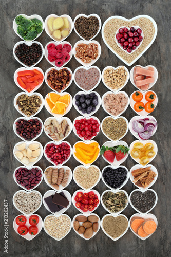 Super food for a healthy heart concept with health foods of fish, fruit, vegetables, pulses, nuts, seeds, grains, cereals with herbs and spice used in alternative herbal medicine. 