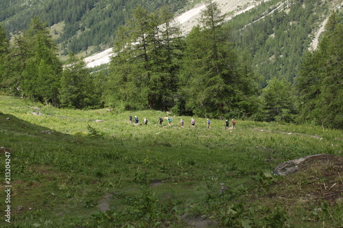 Val D'Aosta, Italy. July 6 2018: group of hikers walking on a pathway on the mountain