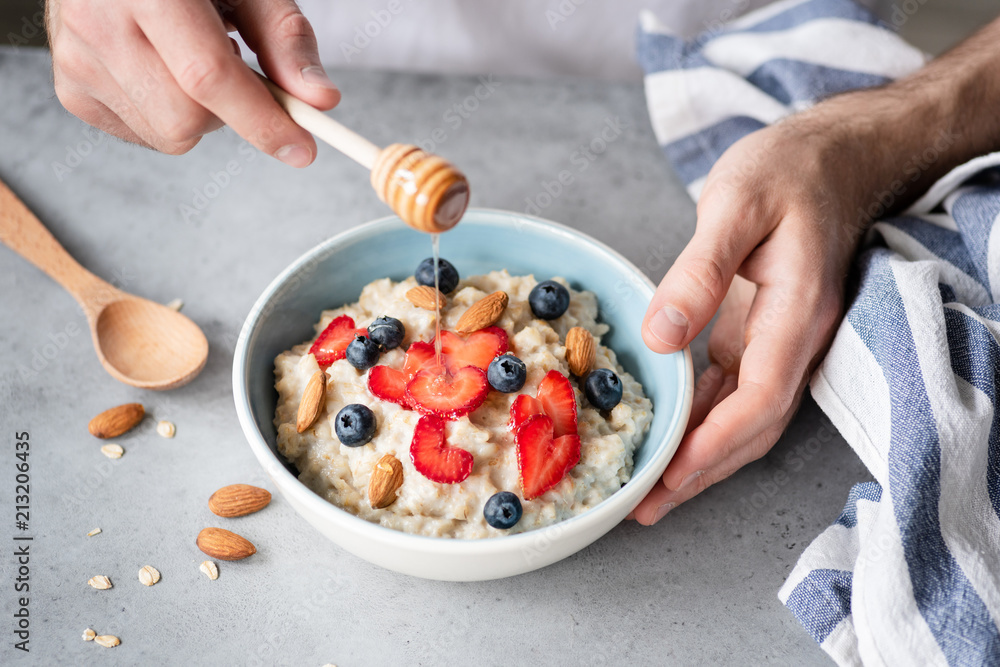 Eating healthy breakfast oatmeal porridge with fresh berries, honey and nuts. Selective focus Eating healthy breakfast oatmeal porridge with fresh berries, honey and nuts. Selective focus