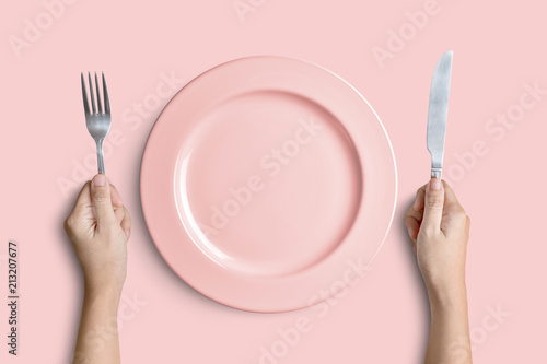 Obraz na plátně Pink plate with silver fork and knife on pink background with clipping path