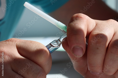 A doctor hand open ampoule and hold with a syringe in his hand  