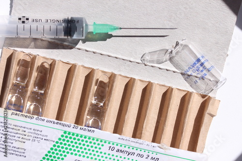 Novocaine in ampoule in the box and syringe on the table.
 photo