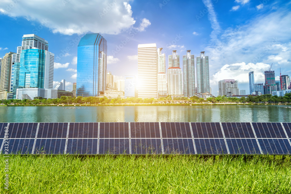Fototapeta premium Solar panel with modern urban construction and skyscrapers background.Alternative energy concept,Clean energy,Green energy.