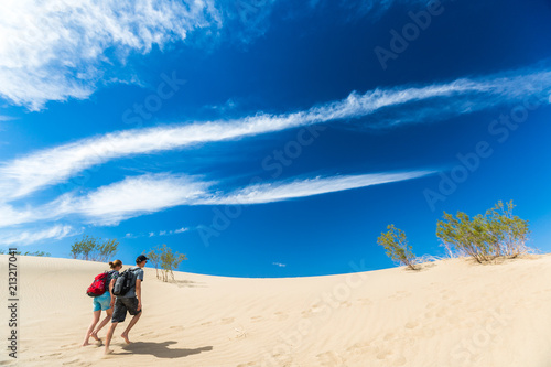Couple of hikers walks barefoot on the sandy desert
