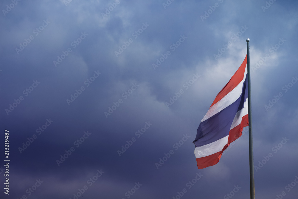 waving Thai flag of Thailand with blue sky background.