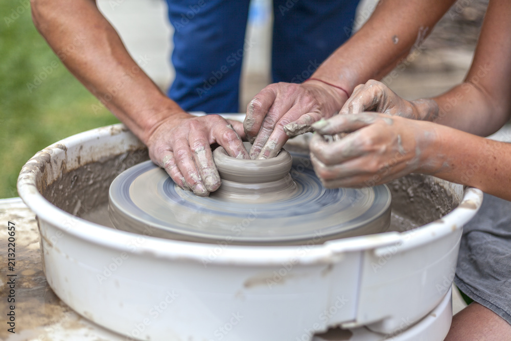 pottery training, a close-up of a woman potter teaches a man how to properly mold a bowl of brown clay on a potter pottery training, a close-up of a woman potter teaches a man how to properly mold a bowl of brown clay on a potter