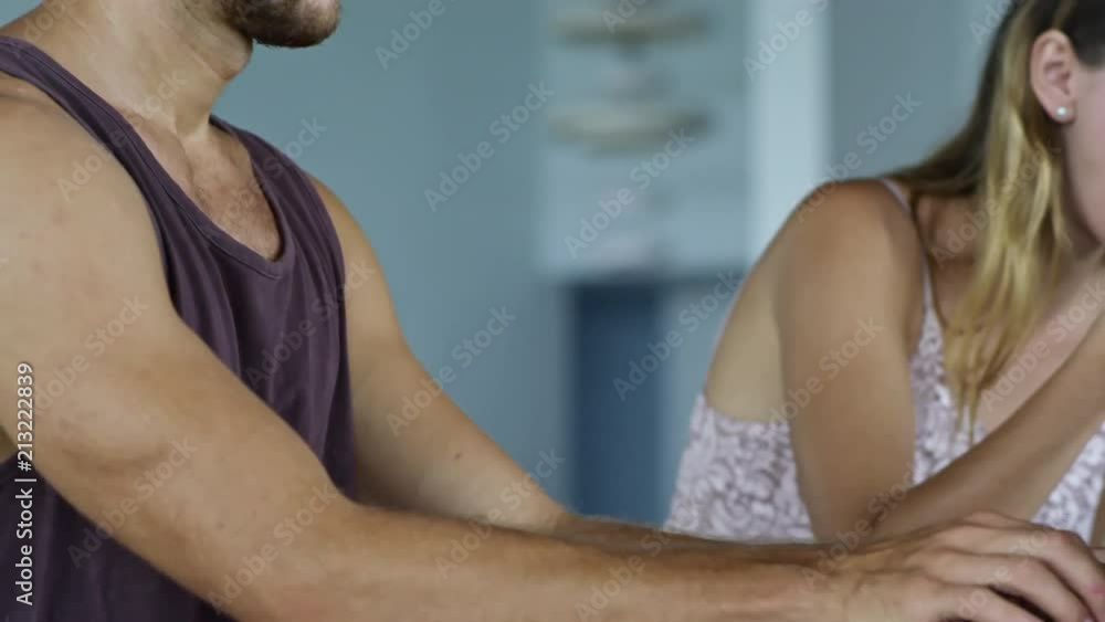 Side view of Caucasian man concentrating on work when using laptop computer, his wife or girlfriend sitting next to him and having breakfast Side view of Caucasian man concentrating on work when using laptop computer, his wife or girlfriend sitting next to him and having breakfast