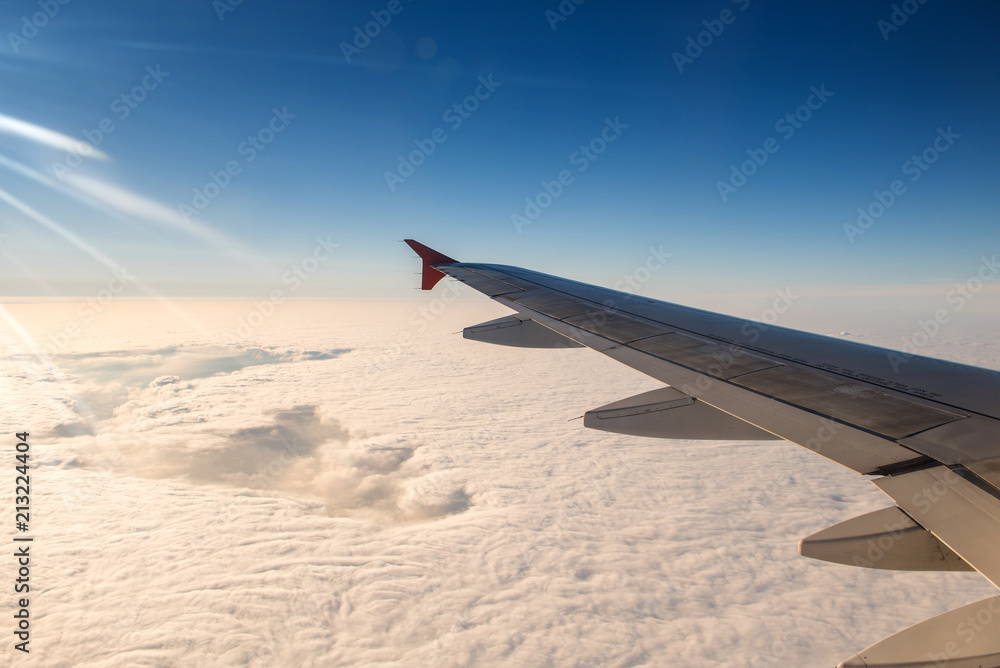 Obraz premium Wing of airplane in with sunrise and blue sky.