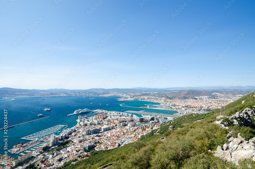 Overall view from top of the Rock of Gibraltar city, cruise port with liner and marina, airport runway, Gibraltar Bay or Bay of Algeciras.