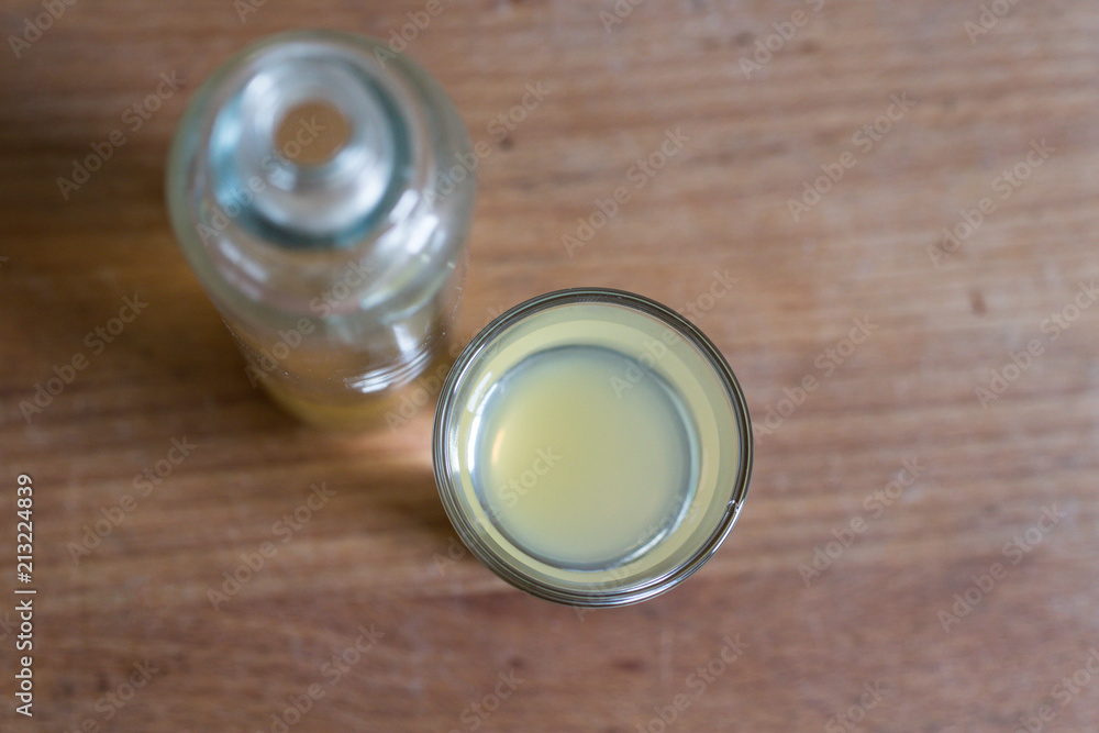 overhead view of glass and bottle with clarifying, detoxing apple cider vinegar for immune defense on wooden table overhead view of glass and bottle with clarifying, detoxing apple cider vinegar for immune defense on wooden table