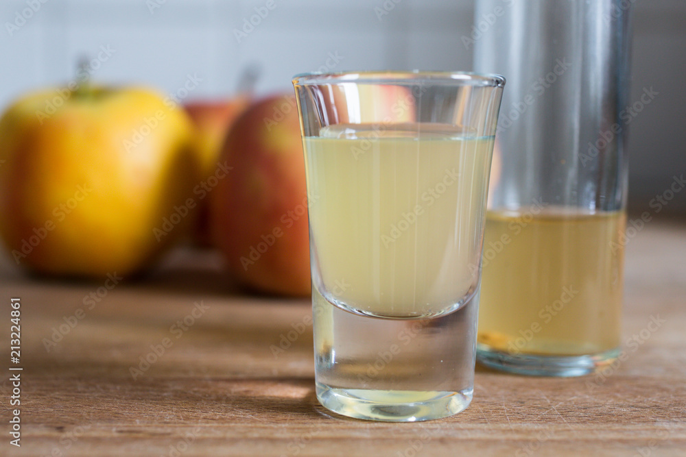 a glass of healthy cloudy fermented apple cider vinegar with apples as decoration on wooden table