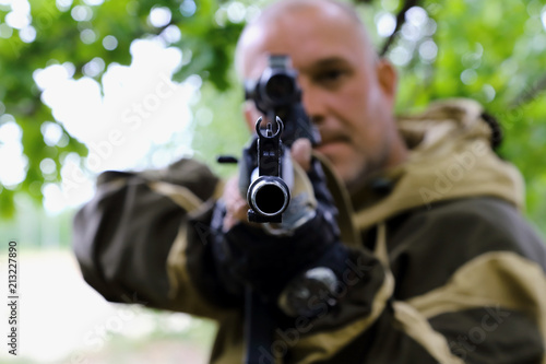 The man hunter is aiming at the gun. Sighting the gun barrel at the target.