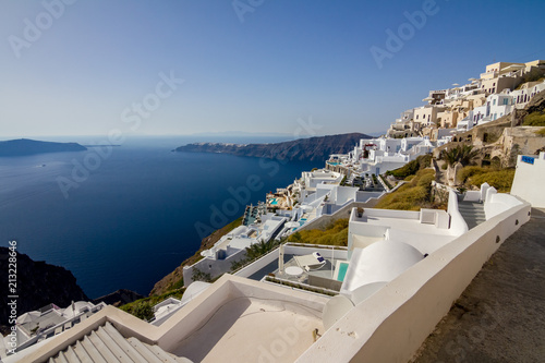 Terrace with view, incredibly romantic scene, Santorini. Fira, Greece. Amazing daytime cityscape towards Oia and the deep sea crystal waters with white houses and swimming pools