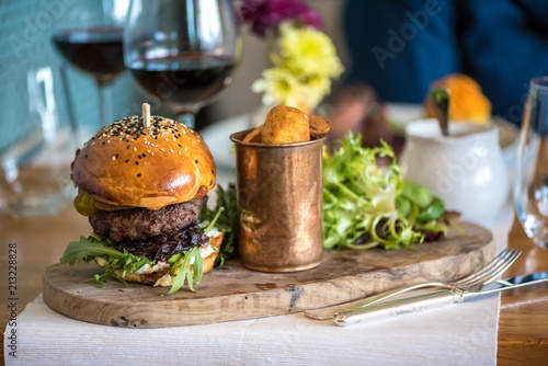 An american beef burger with fried potatoes and red wine
