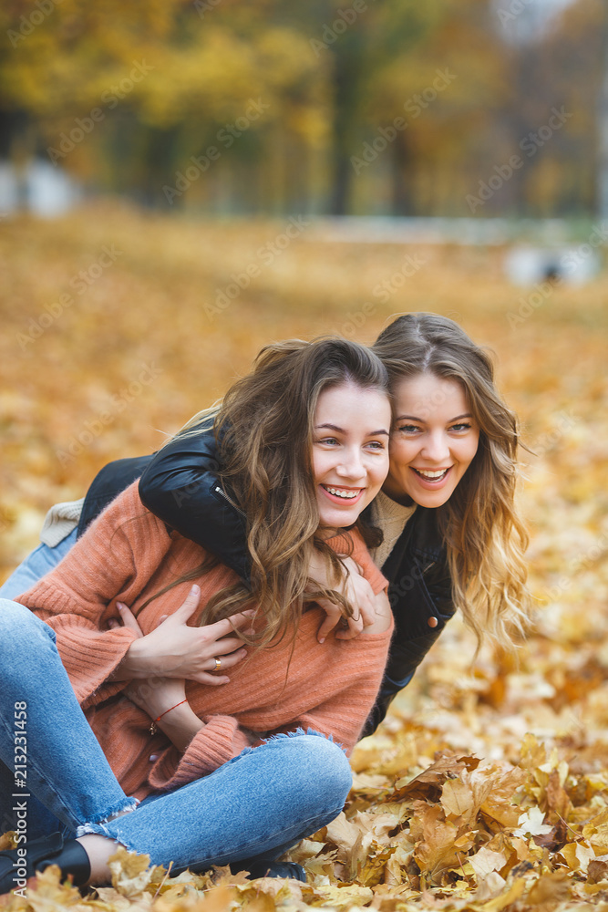 Fototapeta premium Young pretty girls having fun outdoors in autumn background. Cheerful friends in the fall time