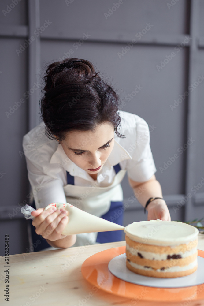 confectioner in a white apron on a dark background with a cupcake confectioner in a white apron on a dark background with a cupcake