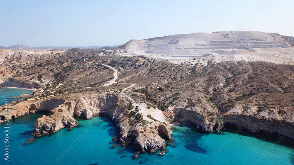 Aerial drone bird's eye view of iconic volcanic white chalk beach and caves of Tsigrado with turquoise and sapphire clear waters, Milos island, Cyclades, Greece