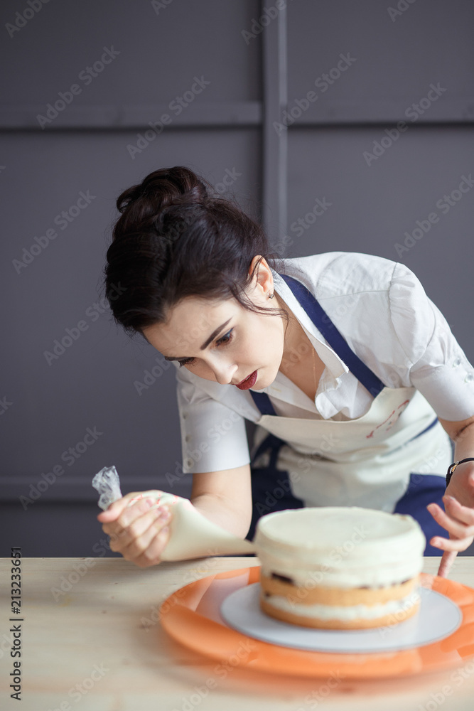 confectioner in a white apron on a dark background with a cupcake confectioner in a white apron on a dark background with a cupcake