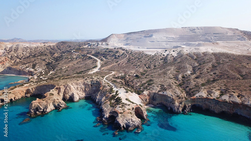 Aerial drone bird's eye view of iconic volcanic white chalk beach and caves of Tsigrado with turquoise and sapphire clear waters, Milos island, Cyclades, Greece