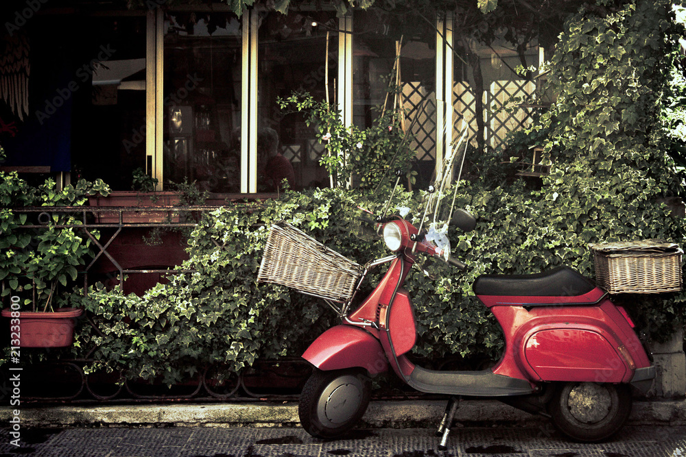 red vintage scooter in italy, retro motorcycle with foliage background