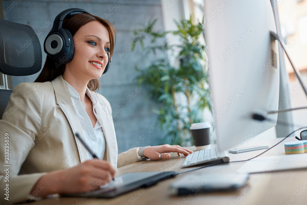 Designer woman wearing headphones and working in design studio. Designer woman wearing headphones and working in design studio.