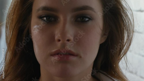 Close up shot of seductive young woman whipping her red hair and flirting while looking at camera