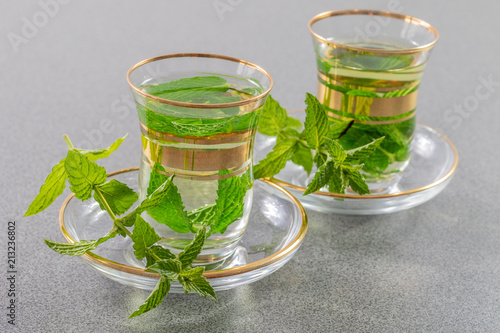 Fresh peppermint tea in glasses on a grey table