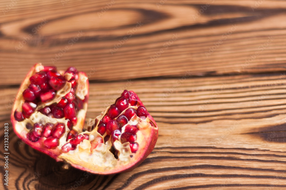 One broken half of red ripe fresh pomegranate on old brown weathered rustic planks One broken half of red ripe fresh pomegranate on old brown weathered rustic planks