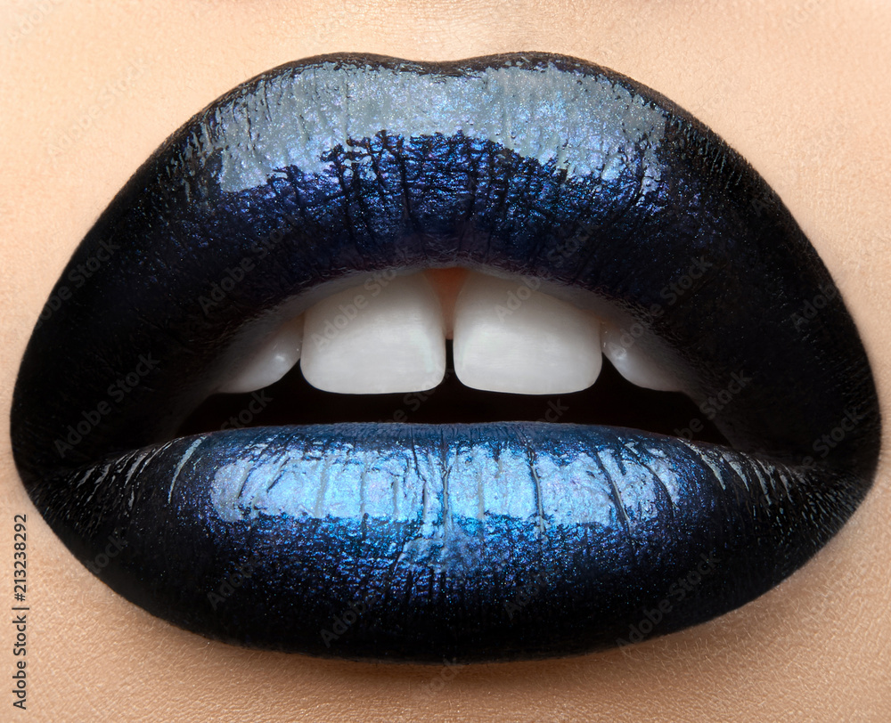 Fototapeta premium Macro and close-up creative make-up theme: beautiful female lips with black and blue lipstick