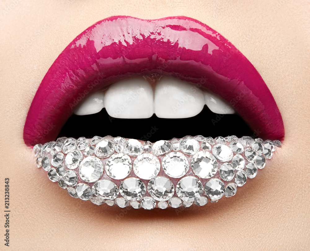 Obraz premium Macro and close-up creative make-up theme: beautiful female lips with pink lipstick, white diamonds and teeth, retouched photo