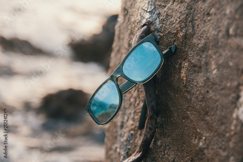 Male sunglasses on the rock near the sea