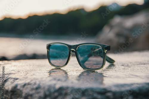 Male sunglasses on the rock near the sea