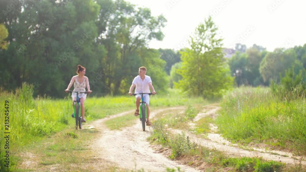 Happy couple cycling on the path in the pine forest Happy couple cycling on the path in the pine forest