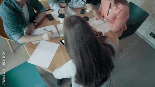 Top dolly shot multiethnic creative business team meeting and brainstorming at round desk diverse people group teamwork discussing in modern start up office female team leader pointing on screen