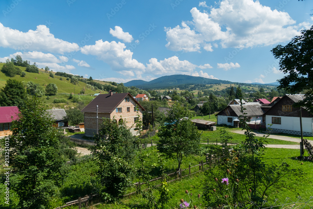 modern and old private residential houses with garden plots and fruit tree gardens in a village on a mountain valley under a blue cloudy sky. place of rest and tourism