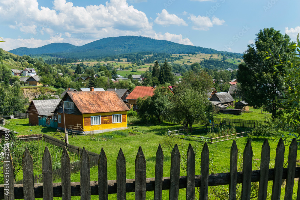 Old wooden fence on the background of a rural mountain village with pretty little houses