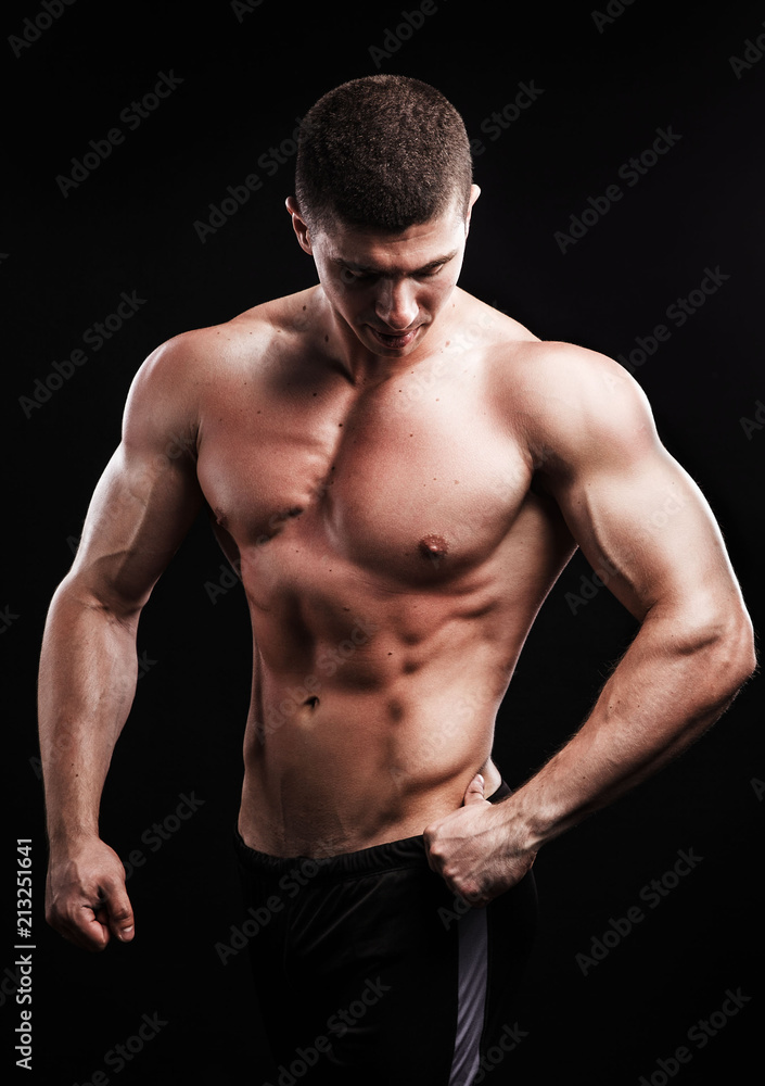 bodybuilder posing. Beautiful sporty guy male power. Fitness muscled man over black background.