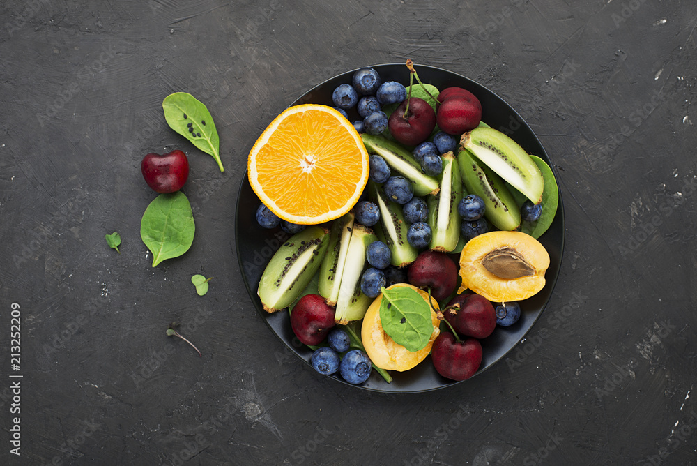 Fruit summer bowl. Orange, kiwi, cherry, spinach, blueberry, apricot plate. Top View.