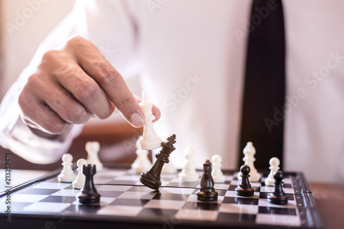Billede på lærred Hand of confident businessman use king chess piece white playing chess game to c